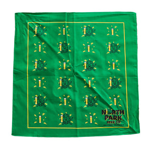 Flat lay photo showing green NPBC bandana with repeating pattern of a hop buddy with lightning bolts and a pilsner glass with lightning bolts.