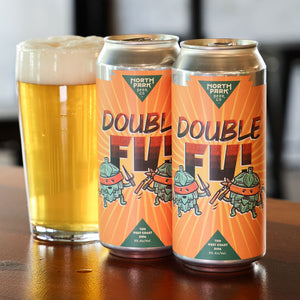 Two cans of North Park Double Fu beer with a glass of beer on a wooden surface.