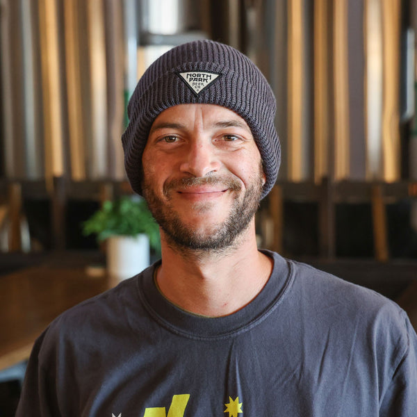Someone wearing gray beanie with triangle patch and dark shirt in an indoor setting