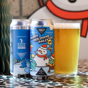 Two cans of 'Happy Holidays, Pally' beer with a glass of beer on a patterned surface.