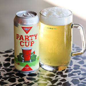 Can of North Park Beer Co Party Cup beer next to a glass of beer on a patterned surface