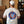Load image into Gallery viewer, Someone wearing  a beige T-shirt with our Simcoe Slammer logo on the back in navy, light blue and orange.
