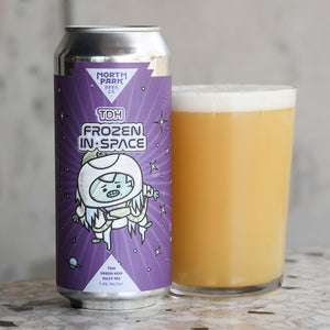 Can of North Park Beer Co. TDH Frozen In Space beer next to a glass of beer on a wooden surface.