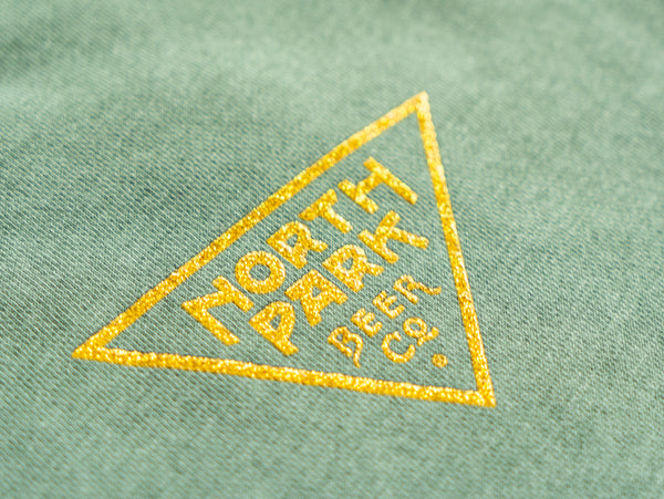 Closeup photo of the NPBC Triangle logo on the front of a green sweatshirt.